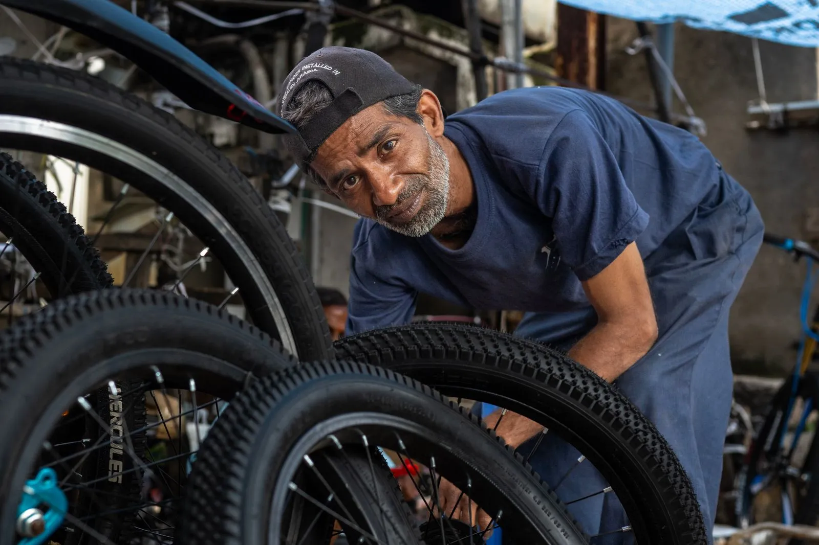 Skilled bicycle mechanic inspecting bike tire in a bustling urban workshop.